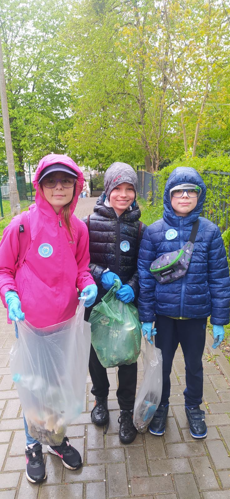 3 uczniów z workami pełnymi śmieci