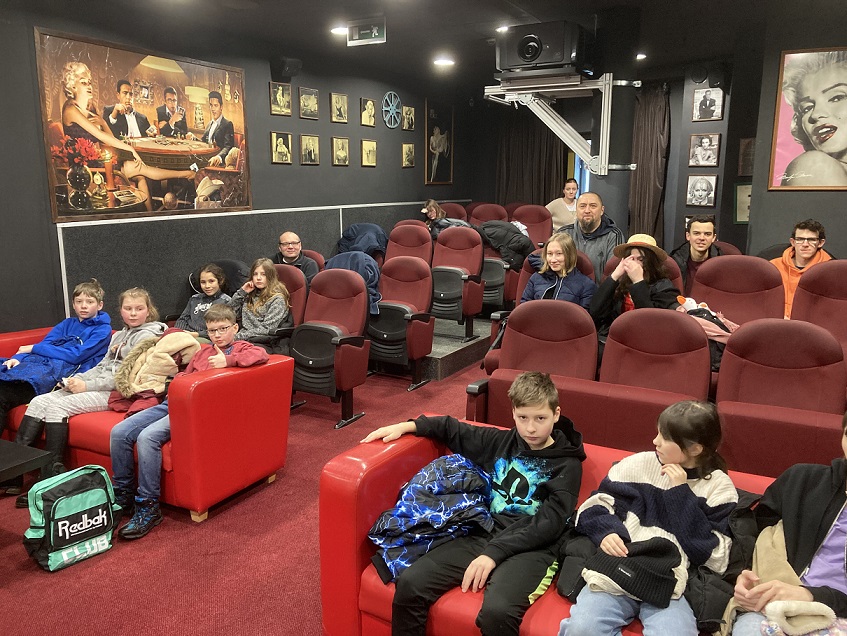 Wolontariusze siedzący na krzesłach w kinie oczekują na film