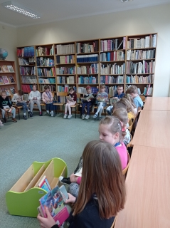 4.	Id- Uczniowie siedzą na krzesełkach w bibliotece, oglądają i czytają wypożyczone książki
